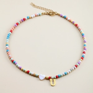 Detail of colorful beaded necklace with white heart charm and gold letter U pendant