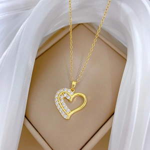 Détail d'un pendentif double cœur doré serti de zircons dans un écrin élégant