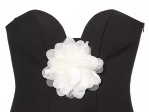 Détail d'un haut bustier noir avec une fleur 3D en résille blanche sur le décolleté
