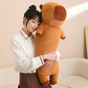 Detailed view of long brown capybara plush pillow held by a woman in cozy setting