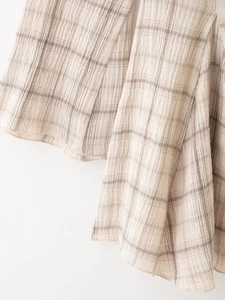Détail du tissu à carreaux beige de la robe à col en V montrant la texture douce