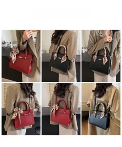 Detailed view of red and black leather handbags featuring silk scarf handles and crossbody straps