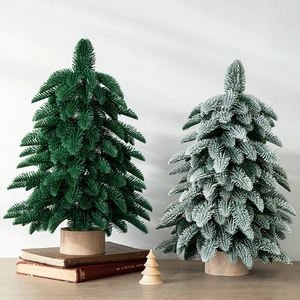 Green and flocked snow mini artificial Christmas trees with natural wood base on tabletop