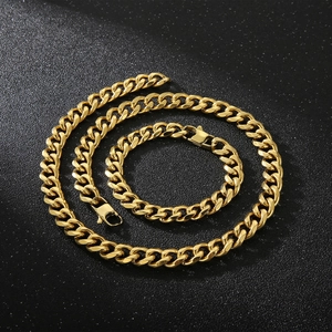 Detail of 11mm gold Cuban link chain set showing necklace and bracelet on black background