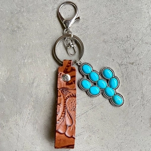 Vintage embossed leather keychain with turquoise cactus pendant on a grey background