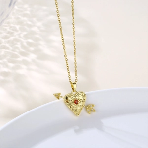Detail of 18K gold heart necklace featuring red zircon and arrow motif with grid texture