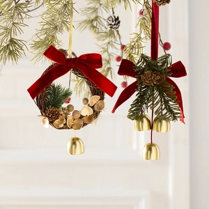 Weihnachtskränze mit roten Samtschleifen und Goldglocken an Kiefernzweigen