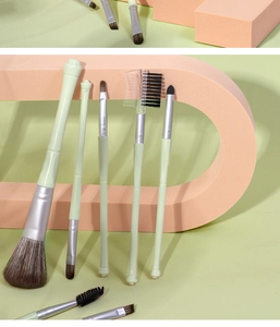 Detailed arrangement of matcha green makeup brushes on soft peach decorative arches