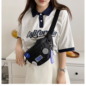 Detail of black nylon chest bag with decorative badges and astronaut charm accessory