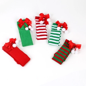 Detailed view of five Christmas over-knee socks with bows and fuzzy pom-poms on white background