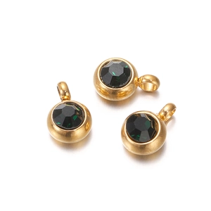 Close-up of golden stainless steel hoop earrings with deep green zircon charms