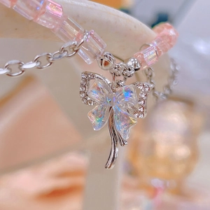 Close-up of pink iridescent square beads and silver rhinestone bow pendant charm