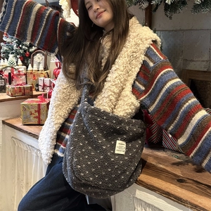 Detail of plush grey heart crossbody bag with white dots and square label on a sweater