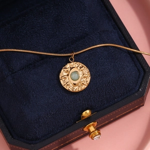 Detail of 18K gold snake chain with turquoise round sunburst coin pendant in a jewelry box