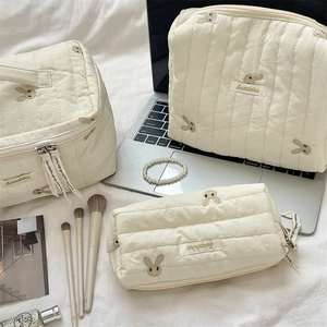Three-piece quilted cotton bunny embroidery organizer bags on a desk with accessories