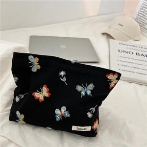 Detail of black fabric pouch featuring colorful butterfly embroidery and flower patterns