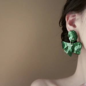 Close-up of a model wearing a dark green marble texture flower earring with rhinestones