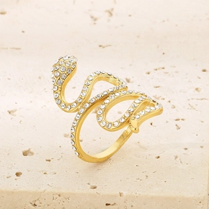 Goldener Schlangenring mit Kristallen auf Steinoberfläche, elegantes gewundenes Design