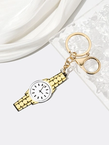 Macro detail of a golden miniature watch keychain with lobster clasp on white silk