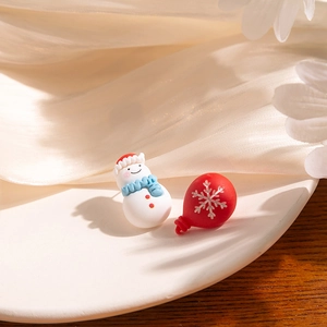 Detailed macro shot of festive Christmas snowman and red snowflake asymmetric studs