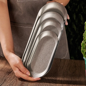 Minimalist oval stainless steel serving trays in vintage style being held by hand