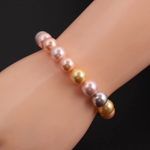 Detail view of multicolored pearl bracelet featuring pink and gold tones on wrist
