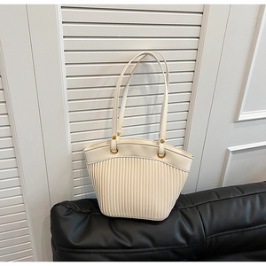 Detail of cream pleated tote bag featuring golden metal rings and leather textures