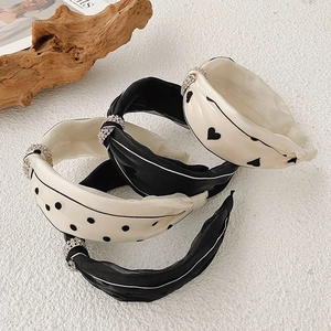 Detailed view of four knotted satin headbands in beige and black with rhinestones