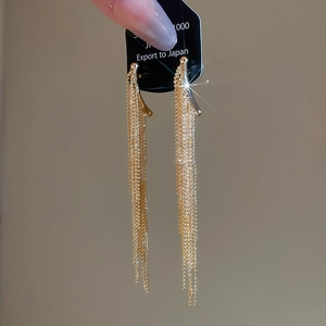 Macro detail of gold-plated long tassel drop earrings with cascading delicate chain layers