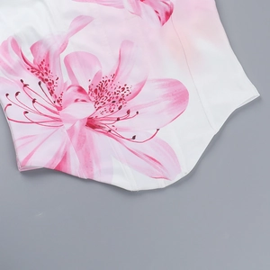 Detailed view of white floral crop top featuring realistic pink lily print and twill texture