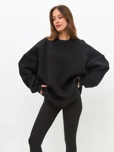 Detailed view of the oversized black crewneck sweatshirt showing loose fit and thick fabric