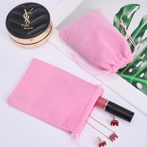 Pair of pink velvet drawstring jewelry pouches on a clean desk with green leaf decor