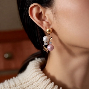 Close-up of elegant gold earrings with white and pink pearls and sparkling diamond accents