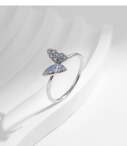 Macro detail of silver butterfly ring featuring light blue opal stones and micro-pave setting