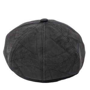 Detailed close-up of geometric paneled stitching on black suede newsboy cap