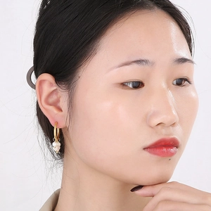 Detail of vintage gold-tone hoop earrings with pearl charms worn by a model