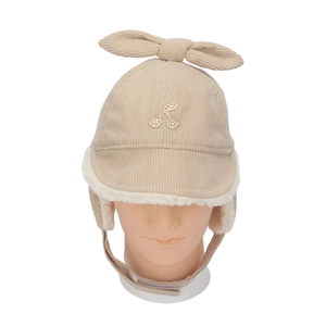 Close-up of beige corduroy kids winter hat with bow and cherry embroidery