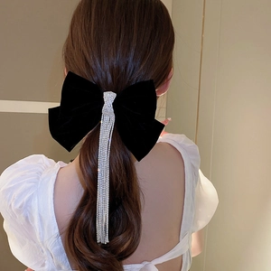 Detail view of a large black velvet bow hair clip with sparkling long rhinestone tassels