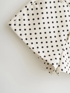 Close-up of black polka dots on beige fabric with premium double-stitch hem detail