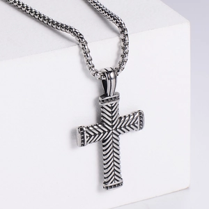 Macro view of silver cross pendant with herringbone texture on a metallic chain