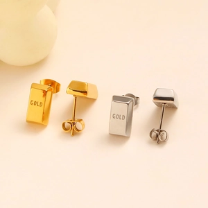 Detail of gold and silver rectangular brick stud earrings with engraved GOLD lettering