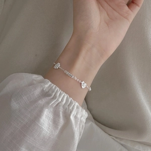 S925 sterling silver bracelet featuring heart and cross charms on a soft fabric background