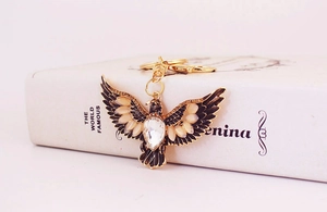 Macro view of gold eagle keychain with white enamel wings and clear crystal inlay