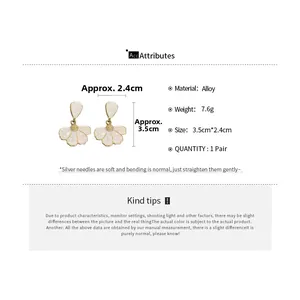 Detail showing white petal flower earrings with gold edges and silver needles measurement