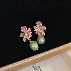 Detailed close-up of gold-plated purple flower earrings with green pearl drops