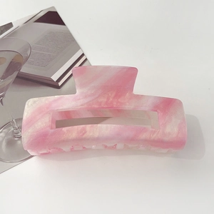 Close-up of pink iridescent marble textured hair claw clip on a minimalist background