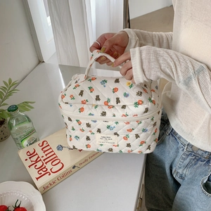 Détail d'une trousse de maquillage en coton matelassé à fleurs avec motif ours et poignée