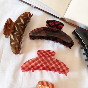 French acetate shark hair clips with checkered pattern displayed on white fabric