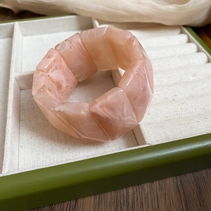 Detail of pink marble acrylic stretch bracelet inside a green velvet jewelry box