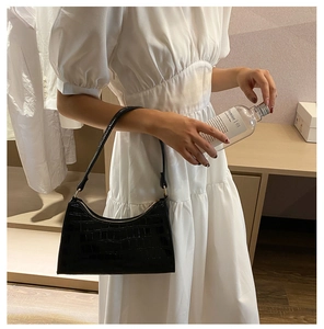 Side view of black crocodile pattern baguette bag on model showing texture and scale